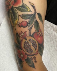 a tattoo of pomegranate and flowers on the arm