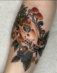 a tattoo of a skull with mushrooms and leaves