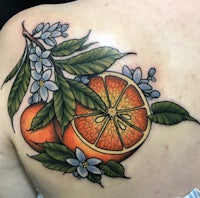 an orange tattoo on the back of a woman's shoulder