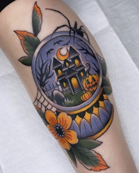 a tattoo of a house and pumpkins on the thigh